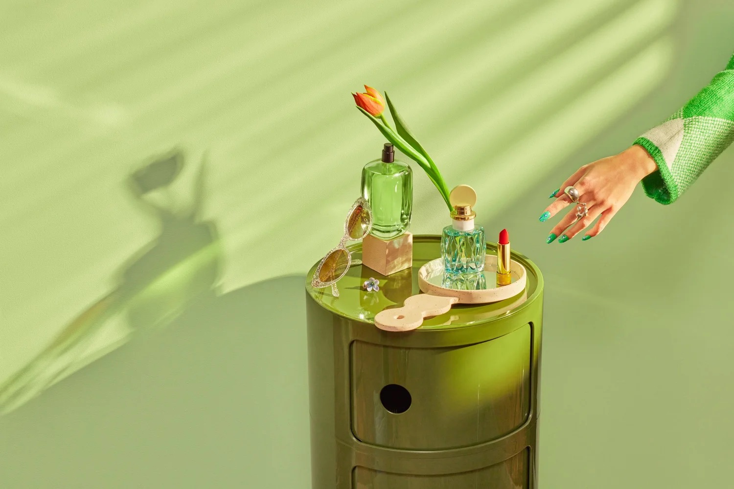 Green tabletop styling with flowers and small objects, modern still life photography