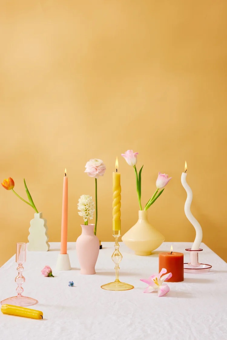 Minimal candles and ceramics on a warm yellow background, styled home goods still life