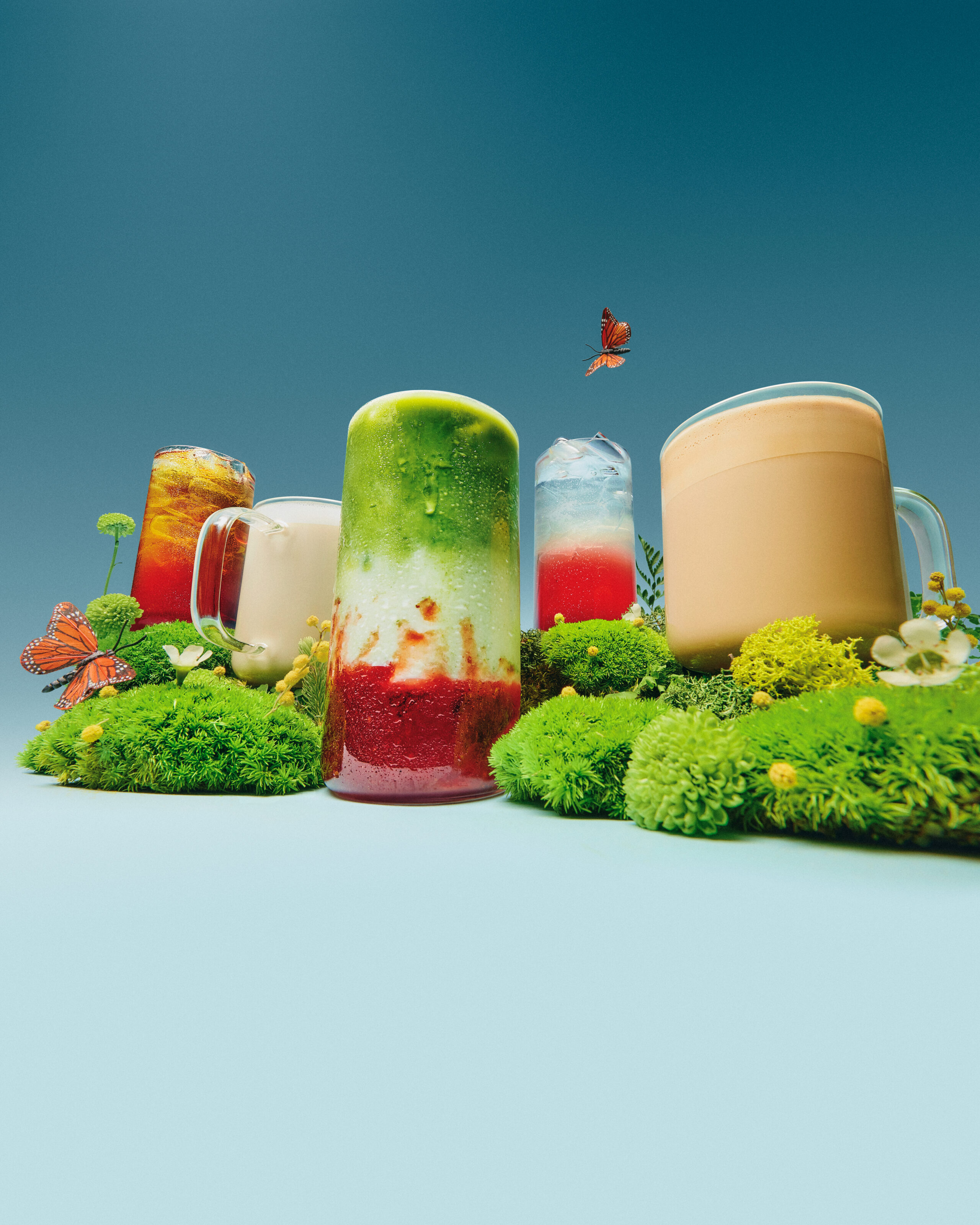 Assorted colorful frozen treats on a pale blue set with moss-like texture, product food photography