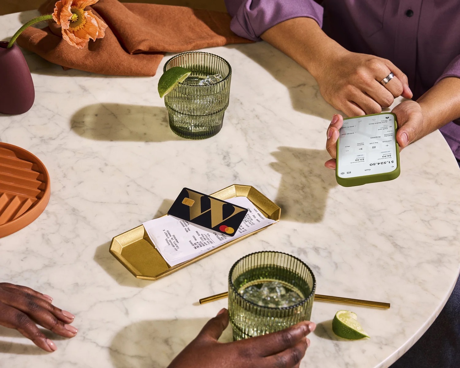 Hands using phone and cards on marble table with drinks in a lifestyle product scene