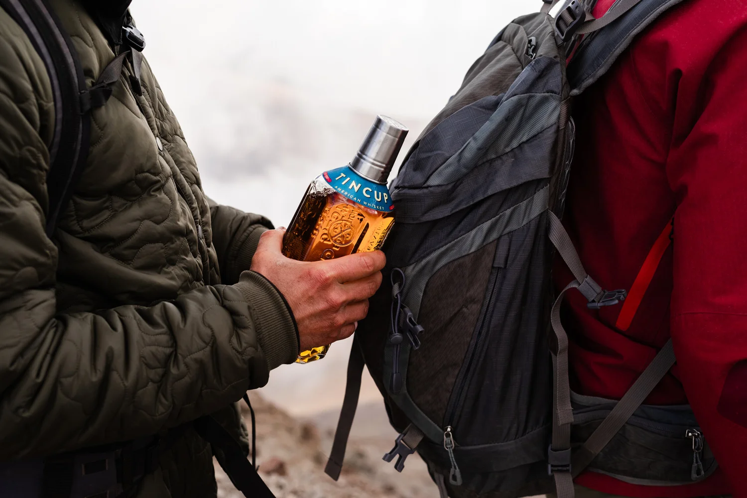 Hand holding a bottle near a jacket, outdoor lifestyle close-up