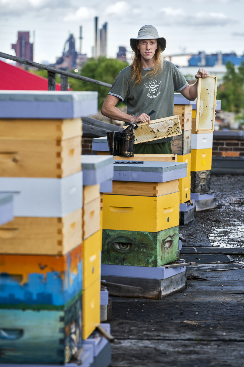 Colorful stacked beehives outdoors with a person working nearby