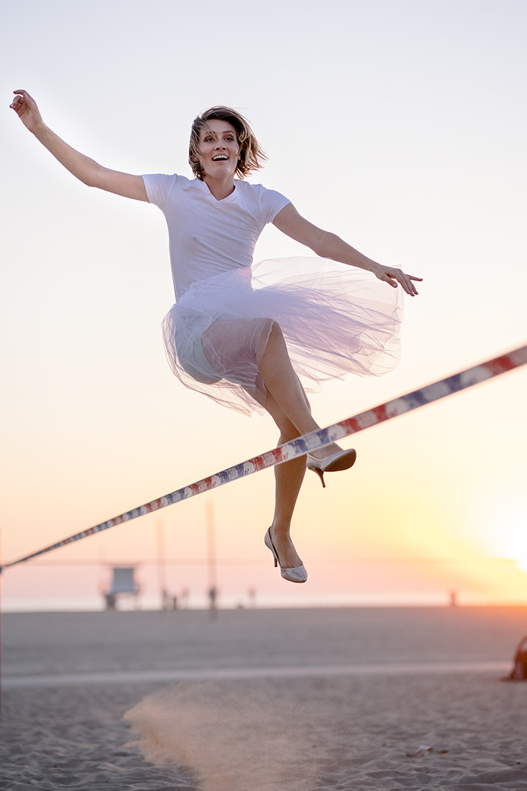 Woman balancing on a slackline at sunset, flowing dress and warm sky