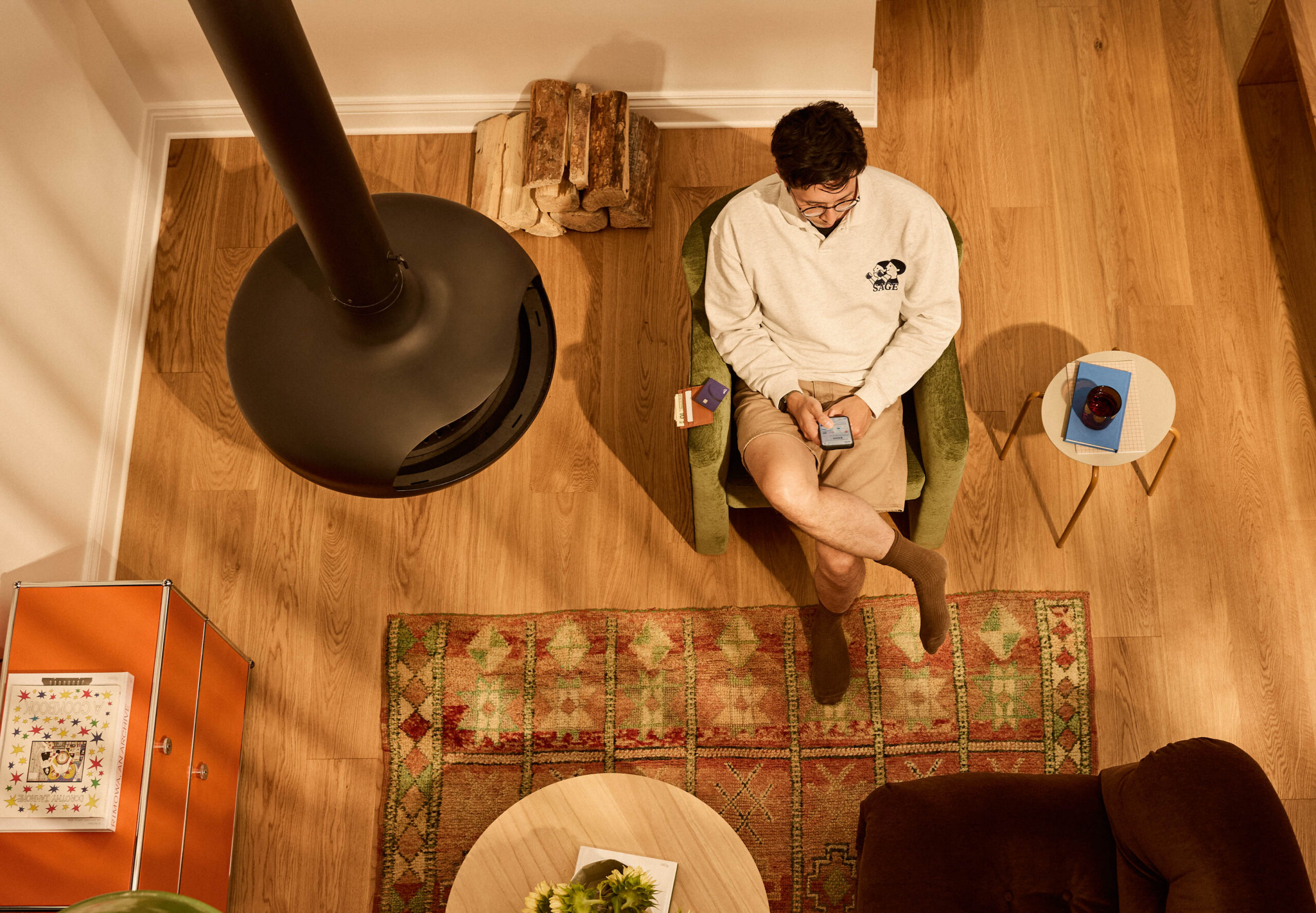 Overhead view of a person sitting in a warm-toned living room using a phone, lifestyle interior photography