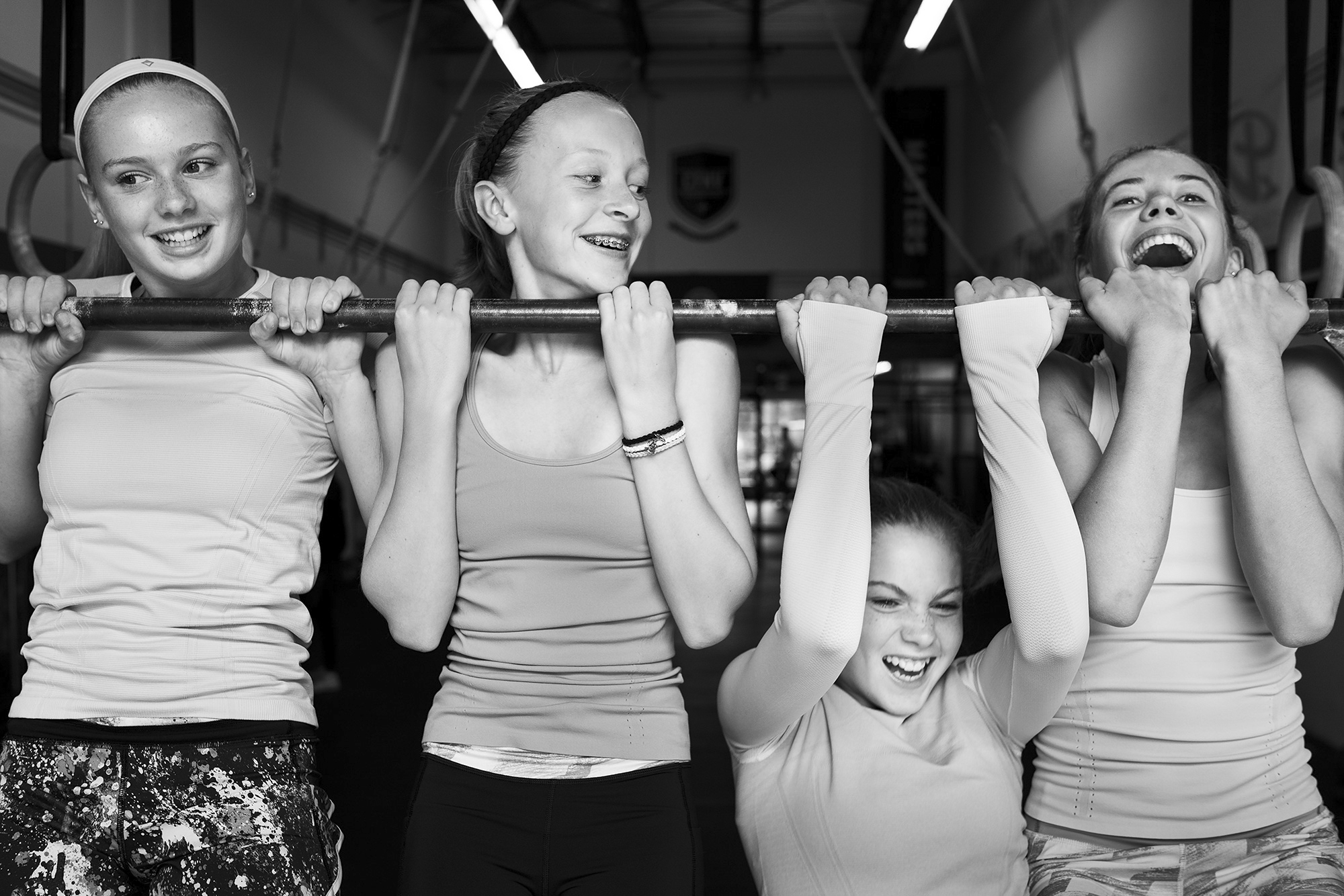 Black-and-white photo of people doing pull-ups indoors, gritty gym atmosphere