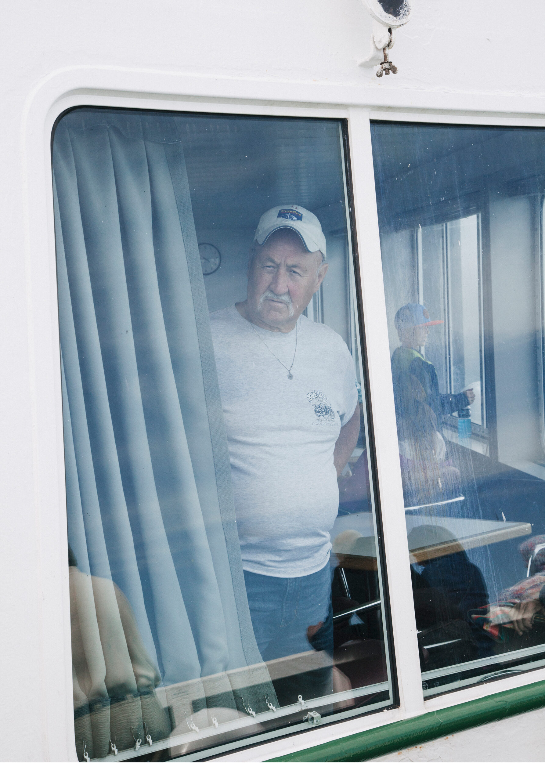 Man standing behind a glass door or window framed by curtains