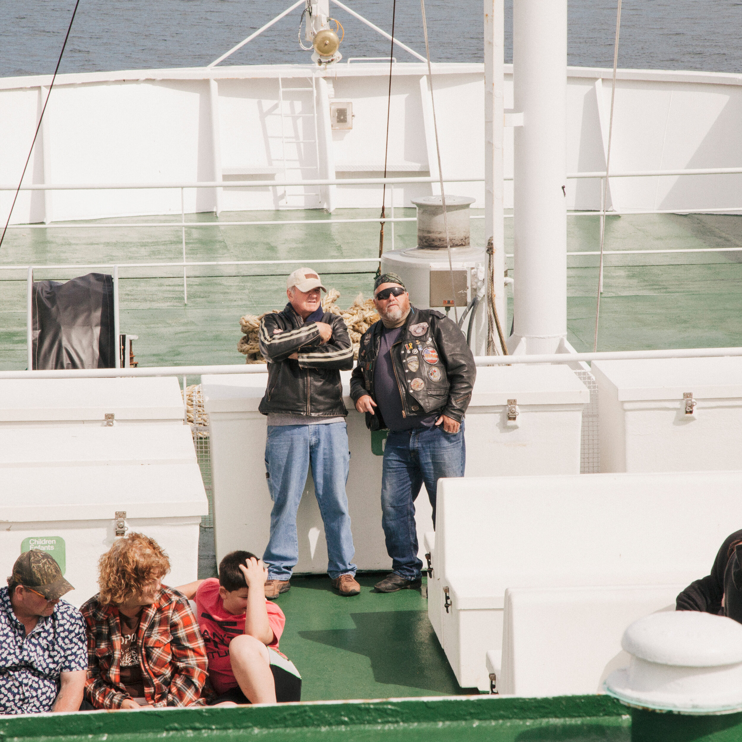 Group of people standing on a boat deck with water in the background