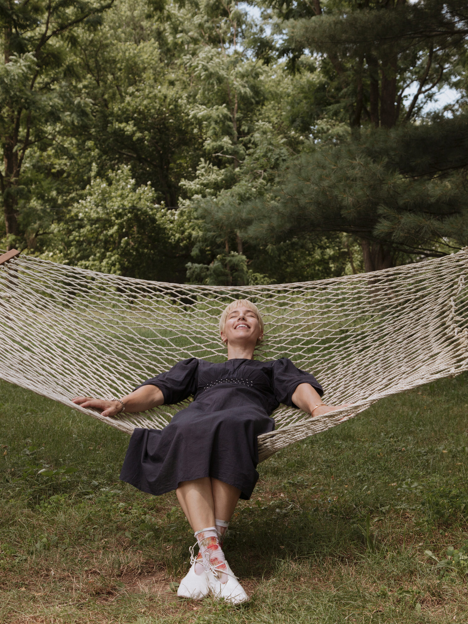 Person lying in a hammock outdoors surrounded by greenery