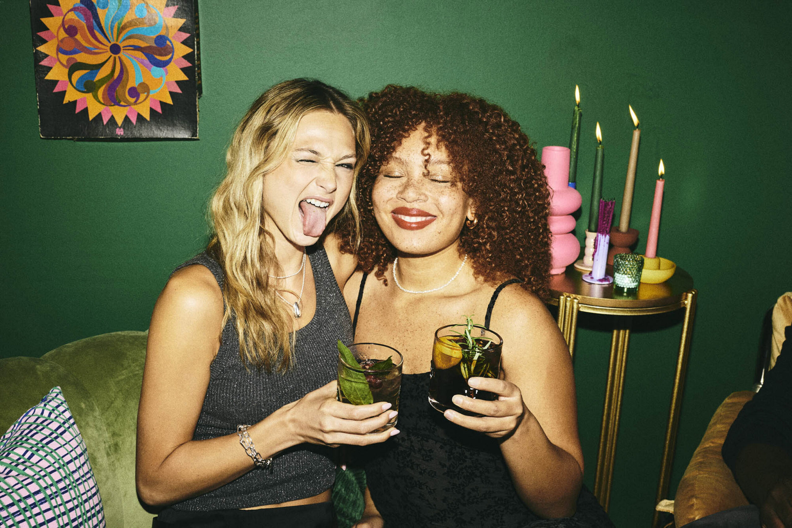 Two women smiling and holding cocktails at a party or social gathering