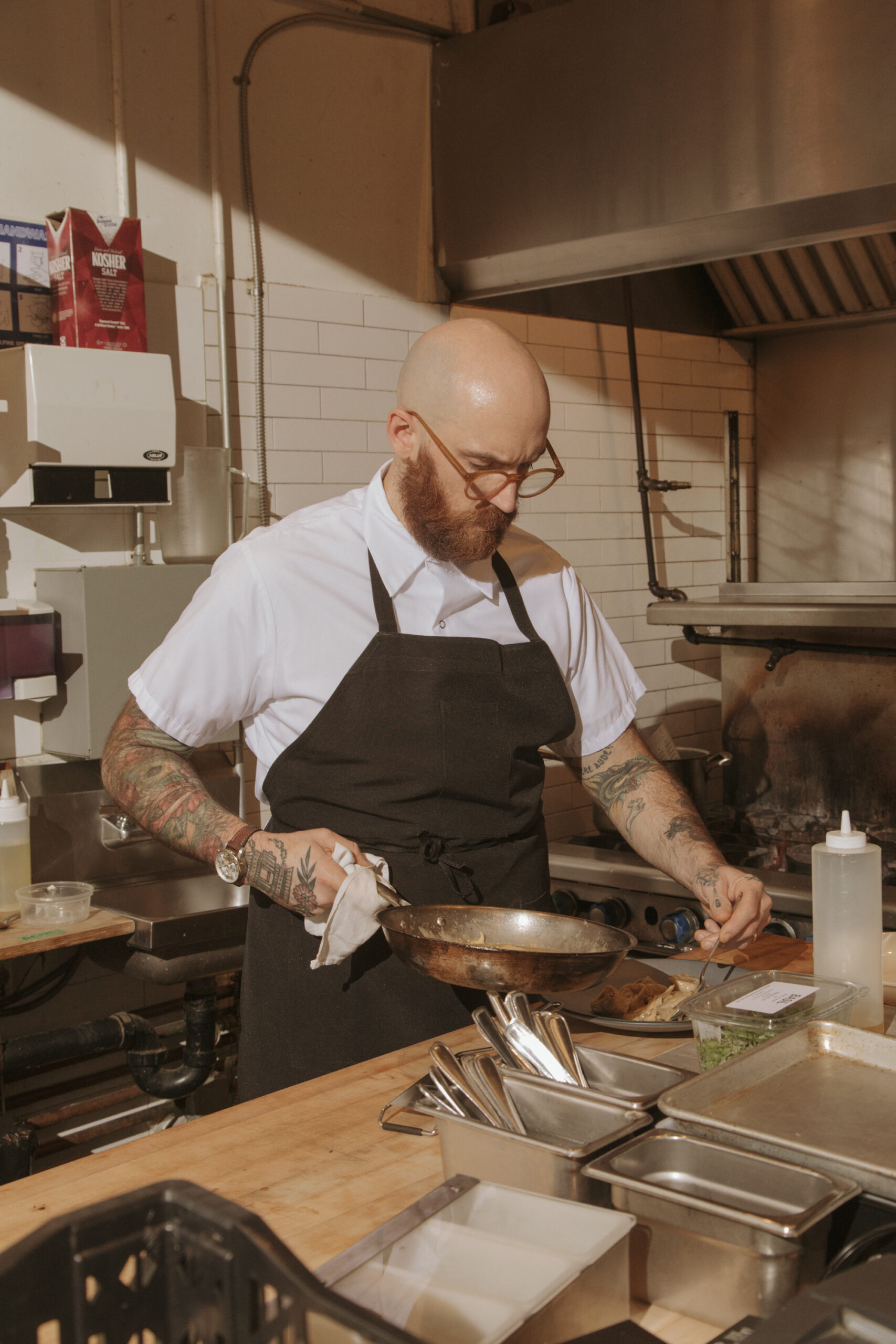 Chef cooking in a kitchen, candid documentary scene with warm light and motion.