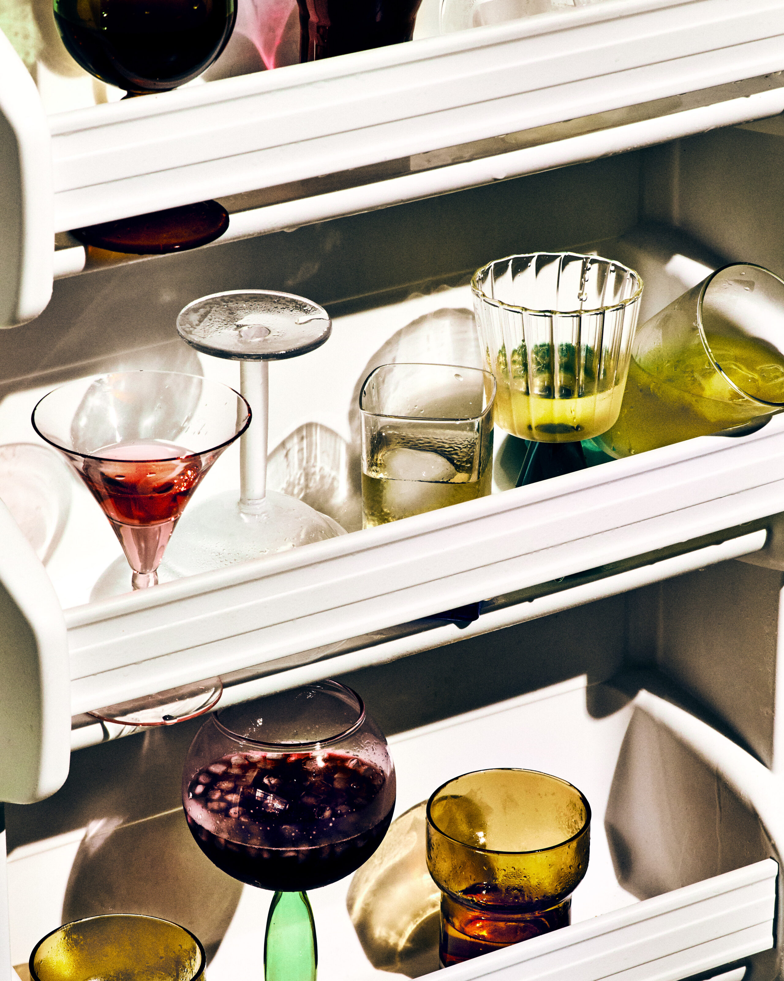 Colorful cocktails and glassware styled on stainless steel shelves or bar surface