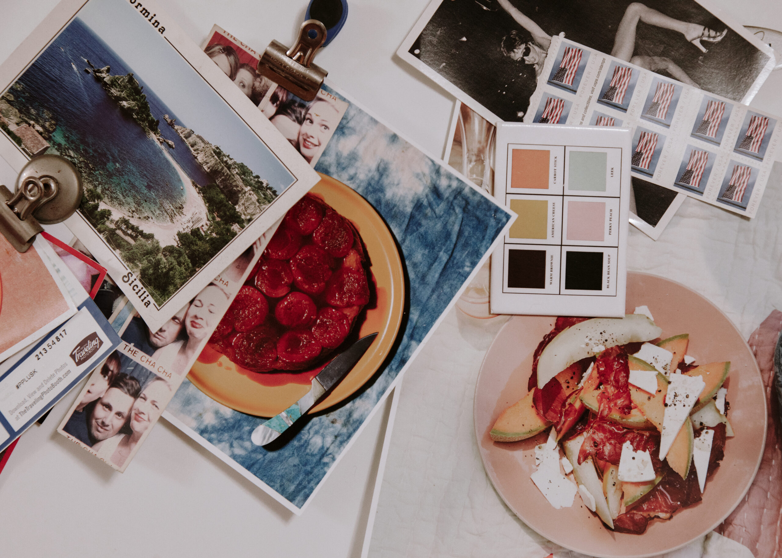 Creative flat lay with printed photos, color swatches, and food styling on a tabletop.
