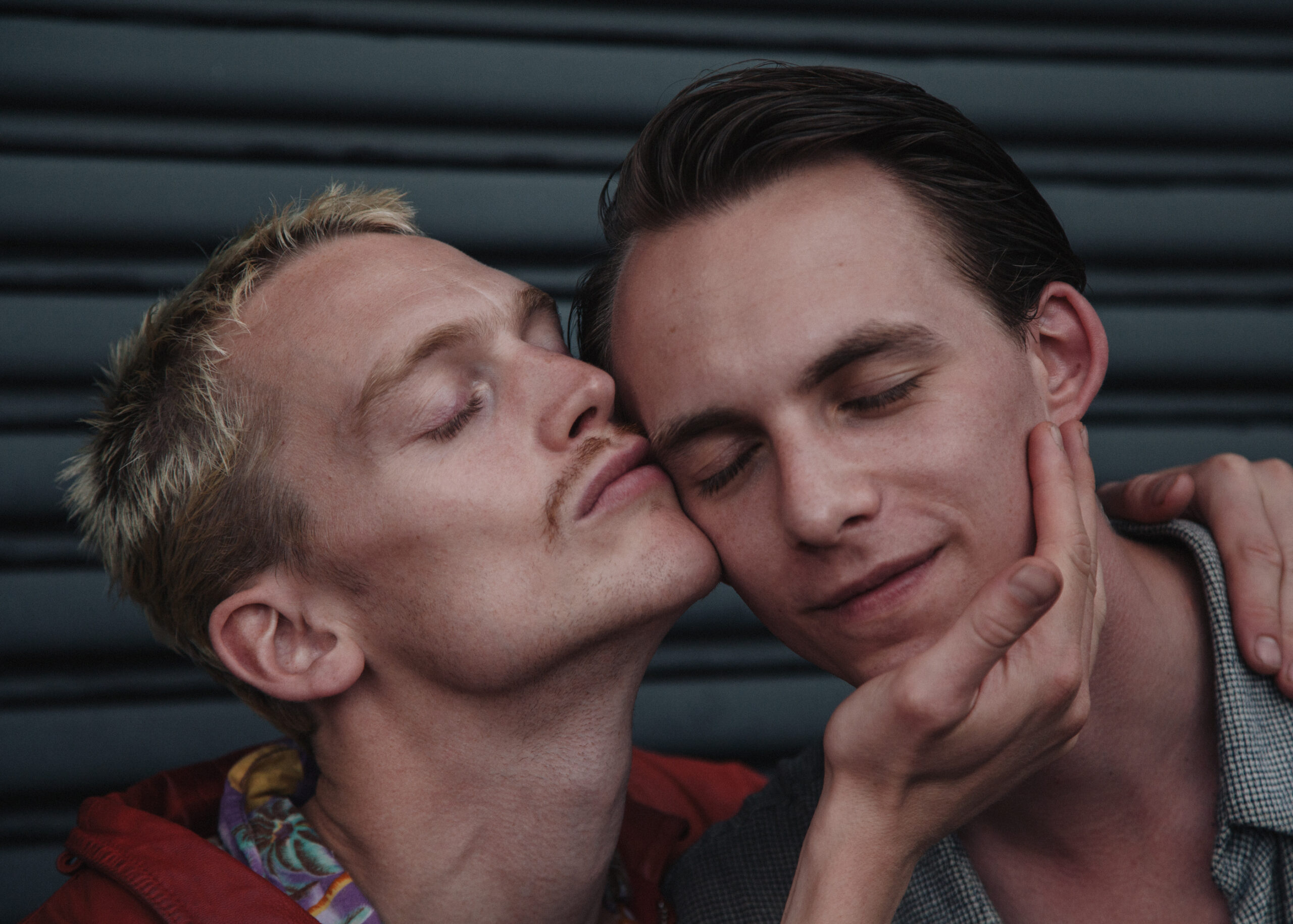 Two men in a close embrace, one kissing the other’s cheek